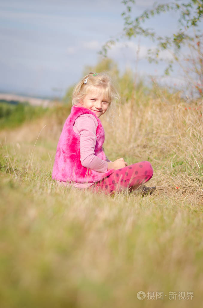 小可爱的女孩坐在草丛中的秋天时间