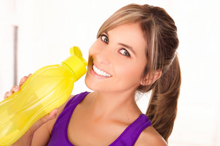 美丽的微笑女人穿紫色 t 恤和喝水黄瓶