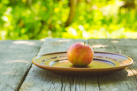 在木制的桌子上的粘土碗红苹果