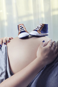 胎儿在孕妇的肚子上的小鞋子