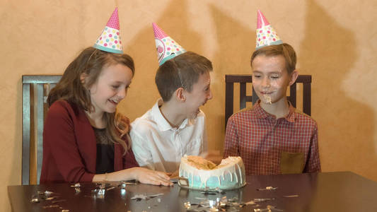在生日聚会上无忧无虑的孩子。孩子们的脸在生日蛋糕