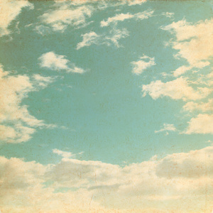 蓝蓝的天空和洁白的云朵在 grunge 风格的旧纸张背景