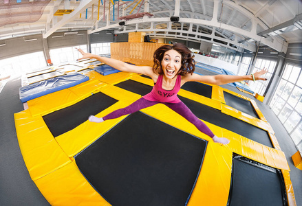 快乐和幸福女人练习和室内体育中心 锻炼和现代娱乐概念在蹦床上跳跃