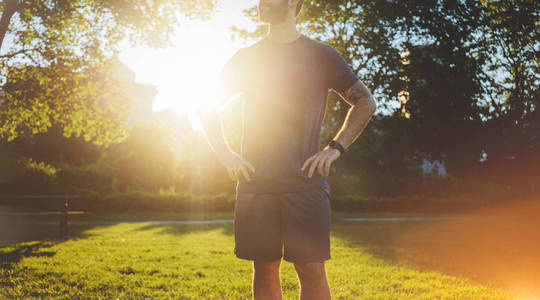 年轻有魅力的男人,在日落的时候在公园跑步后休息照片