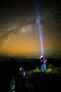 年轻男子站在山与夜晚的天空上