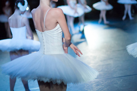 女芭蕾舞演员,穿着短裙,和她的同事们在舞台上玩雪白色礼服背面照片