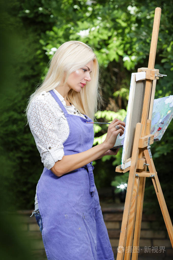女画家与她的手中的画笔在画布上绘制