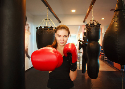 体育的年轻女子拳击在健身房的红色手套