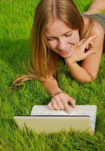 在笔记本电脑上工作的草坪上的女孩