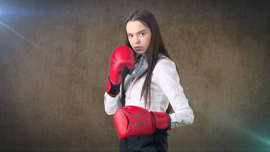 年轻漂亮的女人穿着白衬衫站在战斗的姿势，用红色的拳击手套。经营理念