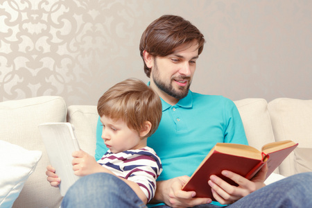 父亲和儿子读一本书或平板电脑