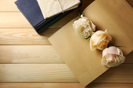 在旧的笔记本，木桌背景上新鲜的玫瑰