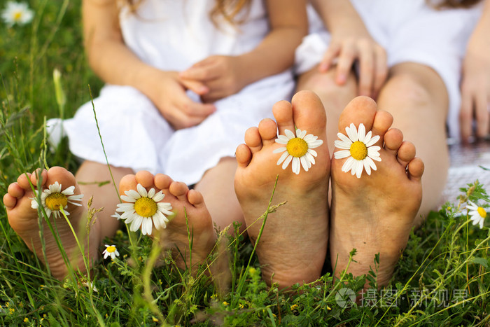 孩子脚与雏菊花在绿色草地上
