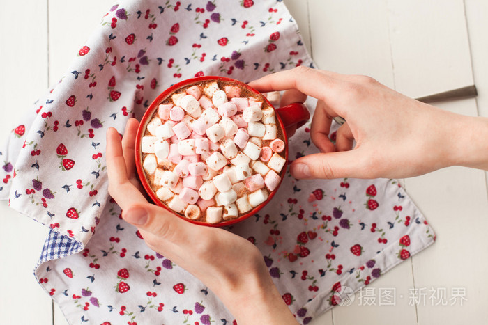 手里捧着杯子里的热巧克力和果汁软糖