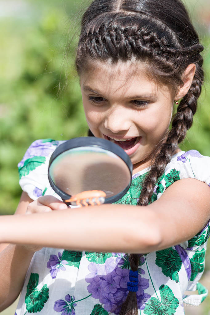 女孩用放大镜和甲虫