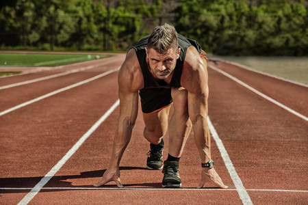 体育背景短跑运动员在大现代体育场前面的跑道上, 带着灯光离开起跑点