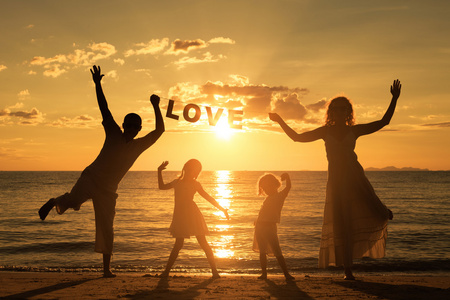 快乐家庭站在海滩上在日落的时候