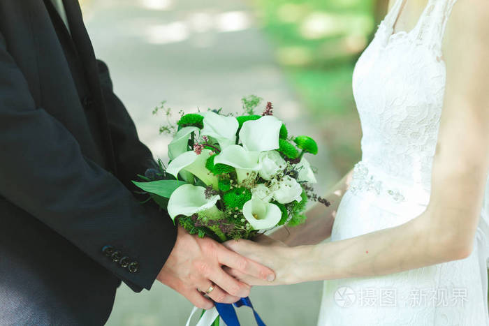 新娘和新郎轻轻地牵手在婚礼上,特写
