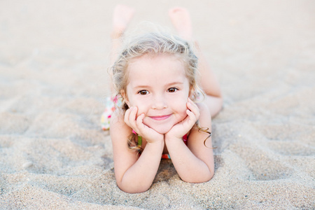 快乐的小女孩躺在沙滩上