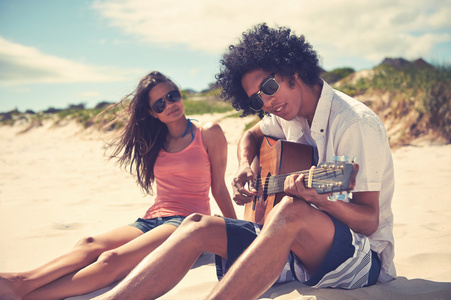 西班牙裔夫妇在沙滩上玩吉他