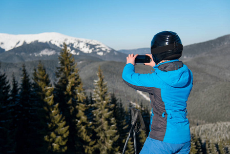 滑雪者使用她拍照的智能手机