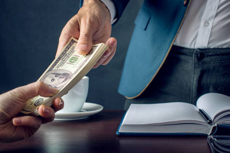 男商人在西装拿钱的手.以美元汇票形式的贿赂.贪污贿赂的概念照片