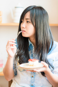 在咖啡厅吃蛋糕的年轻亚洲相当微笑女人的画像