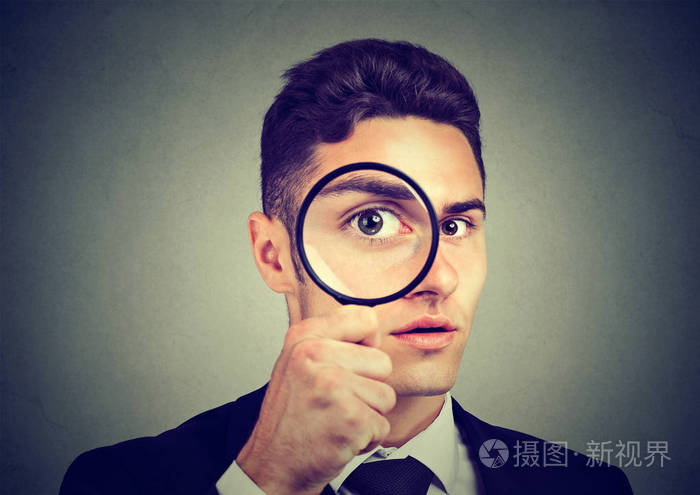好奇心的年轻人透过放大镜看