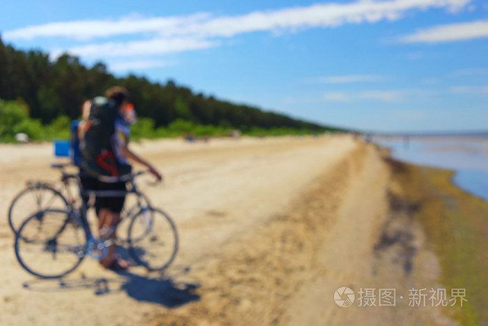 夫妇在海边沙滩上骑自行车旅行。模糊