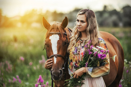 年轻女人站在附近一匹马在草地上一个夏天穿着