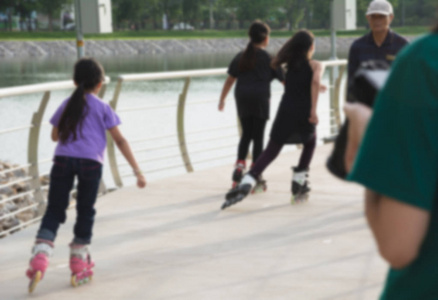 模糊的年轻人在公园玩滚轴溜冰鞋户外。十几岁的女孩在户外的滚轴溜冰鞋