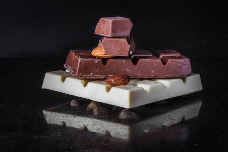 块瓷砖的白巧克力榛子在黑暗的旧有光泽背景和杏仁牛奶巧克力