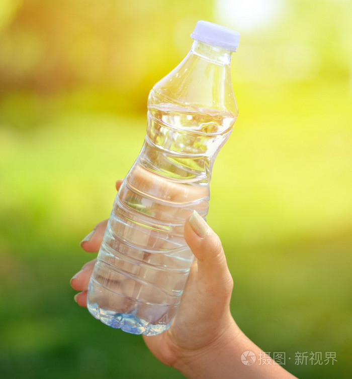 绿色背景拿瓶水的女人手