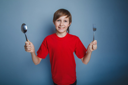 男孩少年一件红色的衬衫，手拿着勺子在欧洲外观