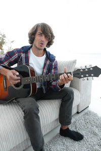 家伙唱一首歌，弹吉他坐在沙发上