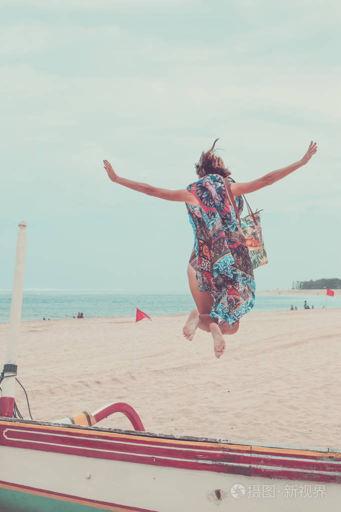 有吸引力的女孩跳上海滩玩乐暑假假期的生活方式快乐的女人跳自由在白