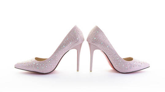 白色背景上的一双粉红色闪闪发光的高跟鞋照片