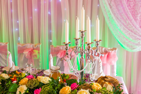 粉红色绿色背景上的宴会桌上的烛台