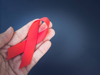 世界艾滋病日的概念。复古手拿着红丝带与黑色背景
