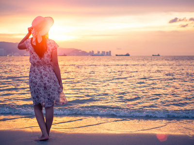 孤独和抑郁的女人拿着一顶帽子站在一个空旷的海滩海前在秋季的一天