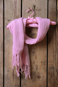 吊架上木板墙背景的粉色围巾