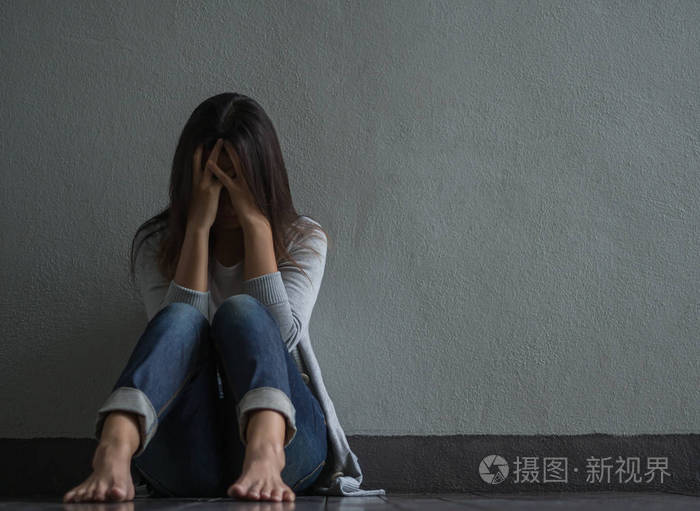 悲伤的女人关闭她的脸,哭时独自坐在空荡荡的房间