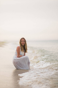 生活方式女人坐在一条白色的裙子在海洋海岸垂直拍摄