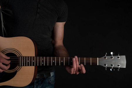 在男性手中，在一个黑色的原声吉他分离背景。水平框架