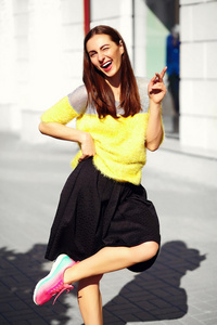 有趣时尚微笑美丽的年轻女子的模型在夏天明亮的黄色时髦布在街上