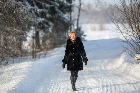 冬天的年轻妇女在雪的路在公园