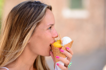 年轻快乐的女人，吃冰激淋室外的肖像