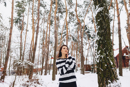 黑色和白色毛衣的年轻女孩在寒冷的森林