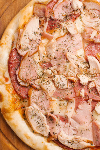 与意大利香肠, 火腿, 鸡肉和芝士干酪在木制比萨饼盘上的特写