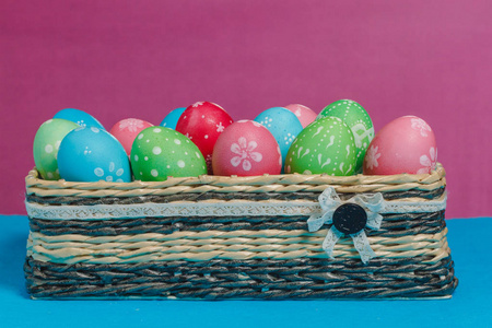 彩色复活节彩蛋在一个蓝色粉红色的背景篮子
